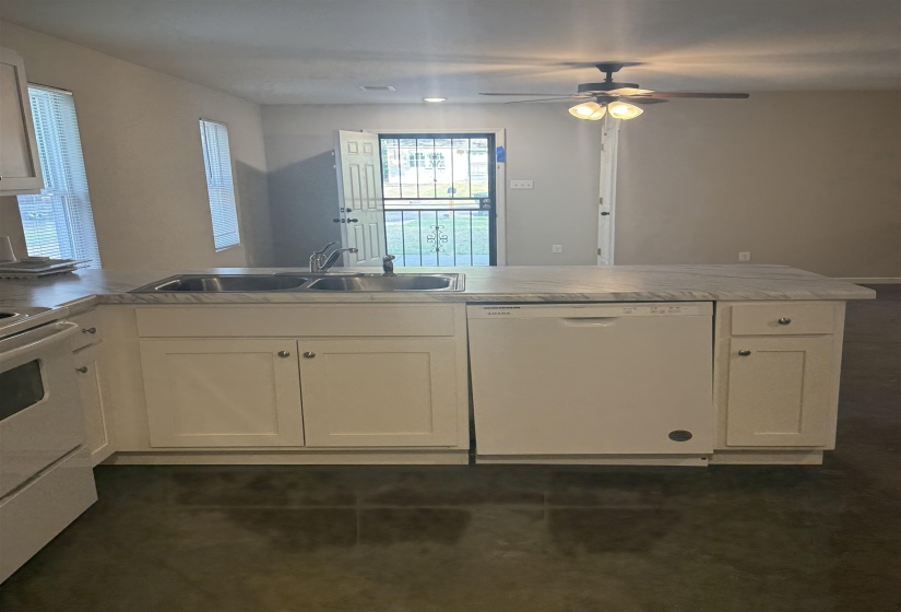 Kitchen with white appliances, a peninsula, light countertops, ceiling fan, and white cabinetry