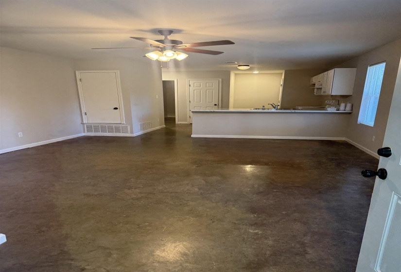 Unfurnished living room featuring concrete flooring and ceiling fan