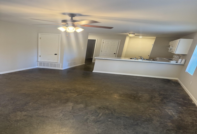 Unfurnished living room with finished concrete flooring and ceiling fan
