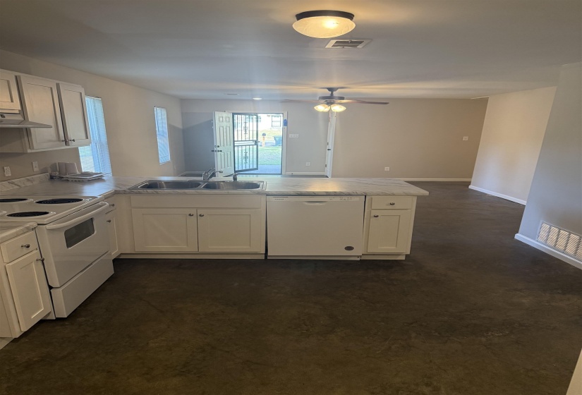 Kitchen featuring white appliances, a peninsula, light countertops, open floor plan, and ventilation hood
