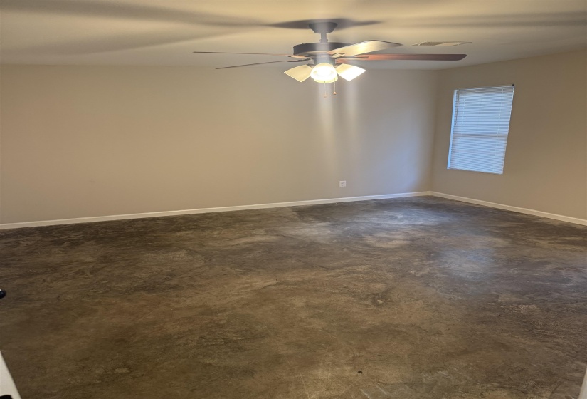 Unfurnished room with concrete flooring and ceiling fan