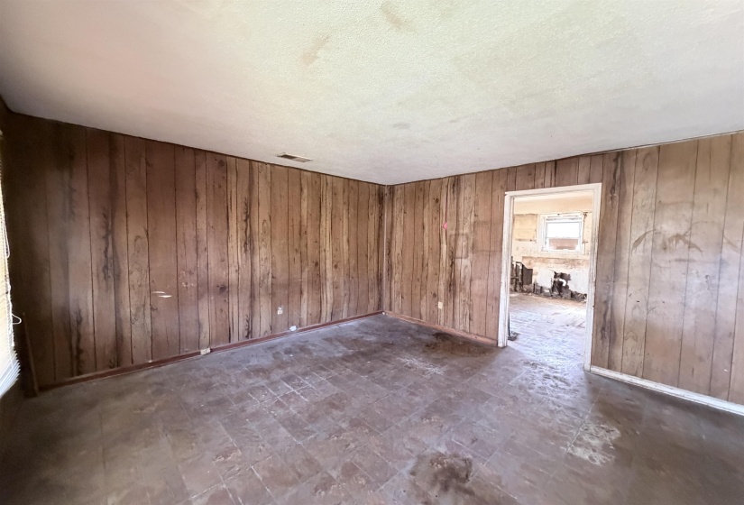 Empty room featuring tile patterned floors, wood walls, and a textured ceiling