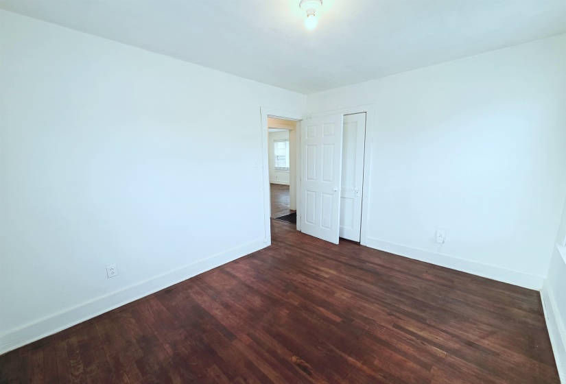 Unfurnished bedroom with dark wood-style flooring and a closet