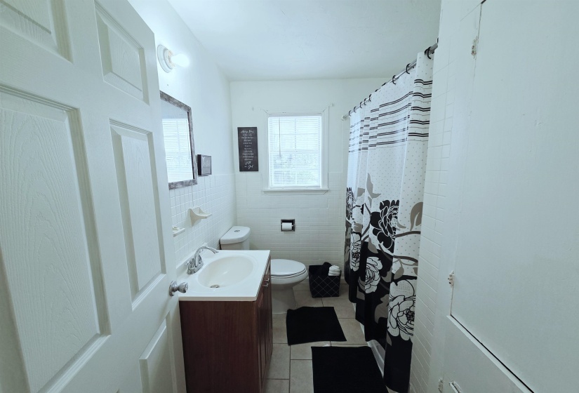 Full bathroom with vanity, light tile patterned floors, a shower with curtain, and tile walls