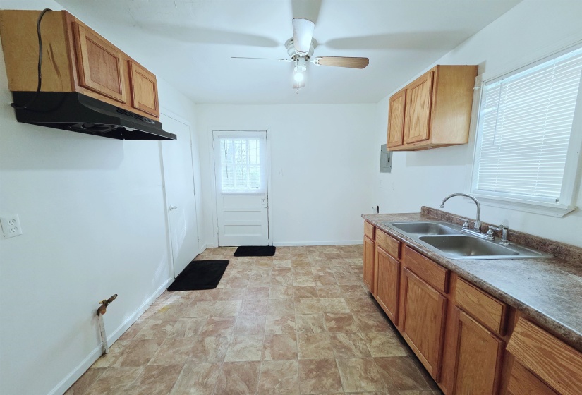 Kitchen featuring stone finish flooring, ceiling fan, wood finish cabinets, and electric panel