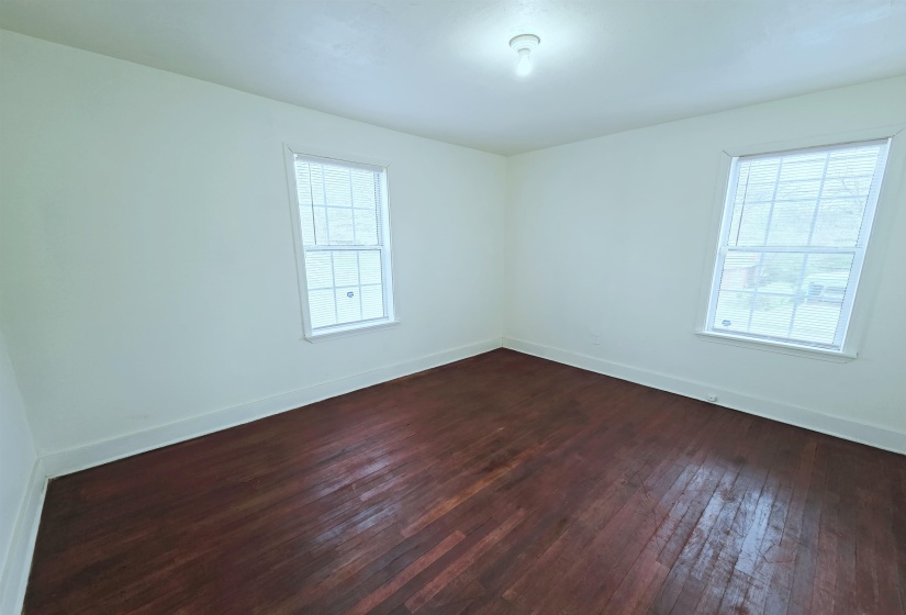 Unfurnished room with baseboards and dark wood-style flooring