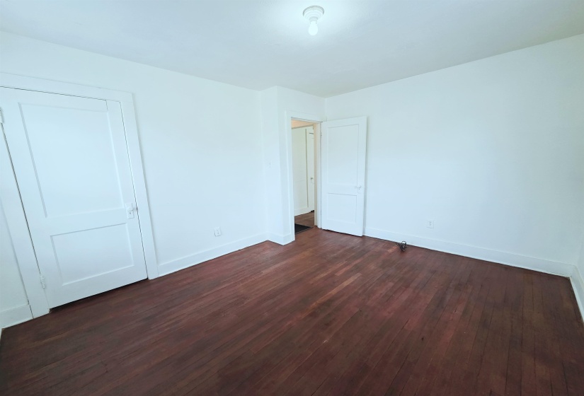Unfurnished bedroom featuring dark wood-style floors and baseboards