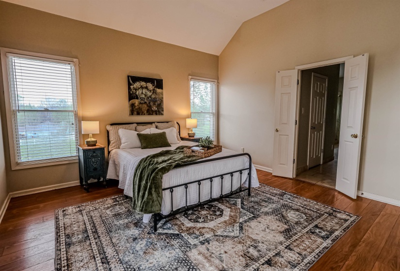Bedroom with hardwood / wood-style flooring, baseboards, and vaulted ceiling