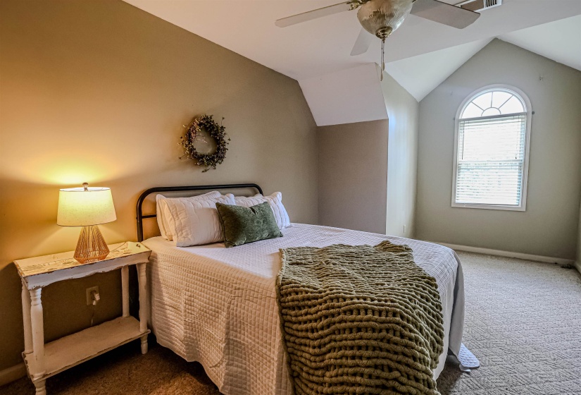 Carpeted bedroom with baseboards, vaulted ceiling, and ceiling fan