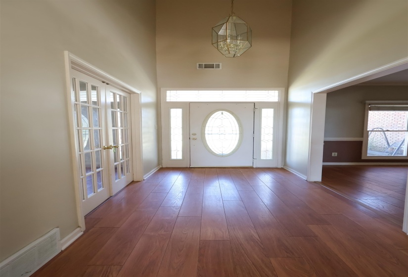 Foyer entrance with french doors, dark wood-type flooring, and a towering ceiling