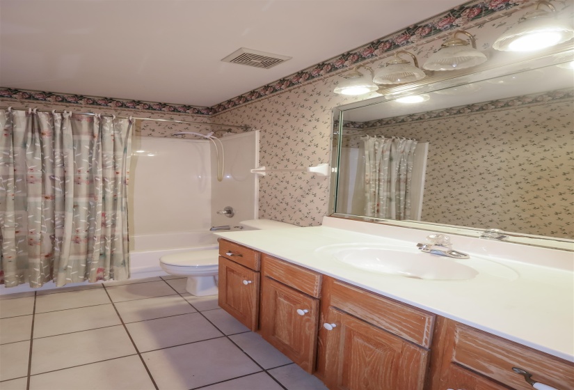 Full bathroom with tile patterned flooring, vanity, toilet, and shower / bath combo with shower curtain
