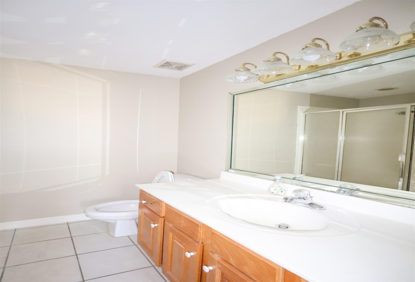 Bathroom with tile patterned floors, toilet, a shower with door, and vanity