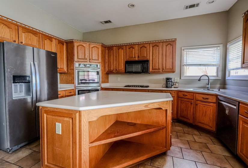 Kitchen featuring open shelves, a center island, a sink, visible vents, and appliances with stainless steel finishes