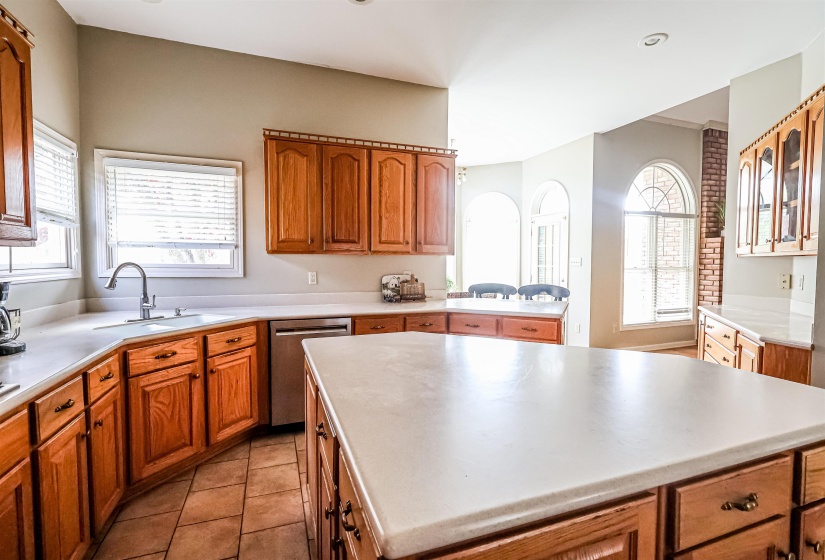 Kitchen featuring brown cabinetry, a sink, stainless steel dishwasher, and a center island
