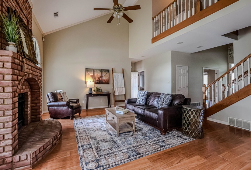 Living area featuring a ceiling fan, wood finished floors, baseboards, and visible vents