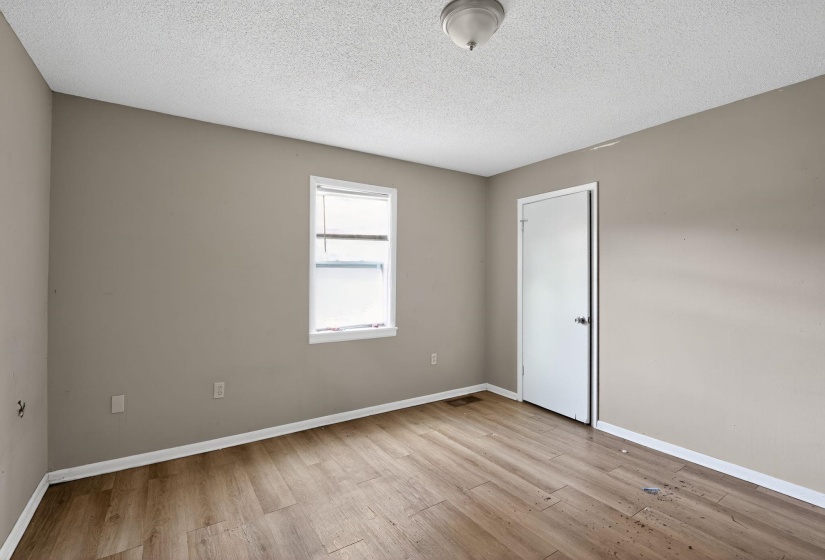 Empty room featuring light wood-type flooring and a textured ceiling