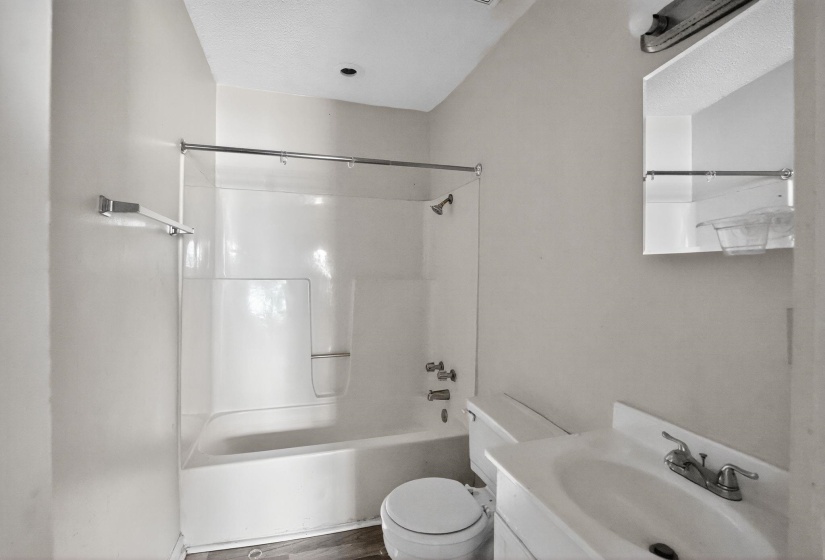 Full bathroom featuring vanity, tub / shower combination, dark wood-style flooring, and a textured ceiling