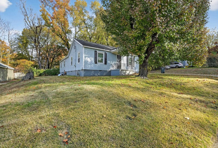 View of front of home with a front lawn, crawl space, and view of scattered trees