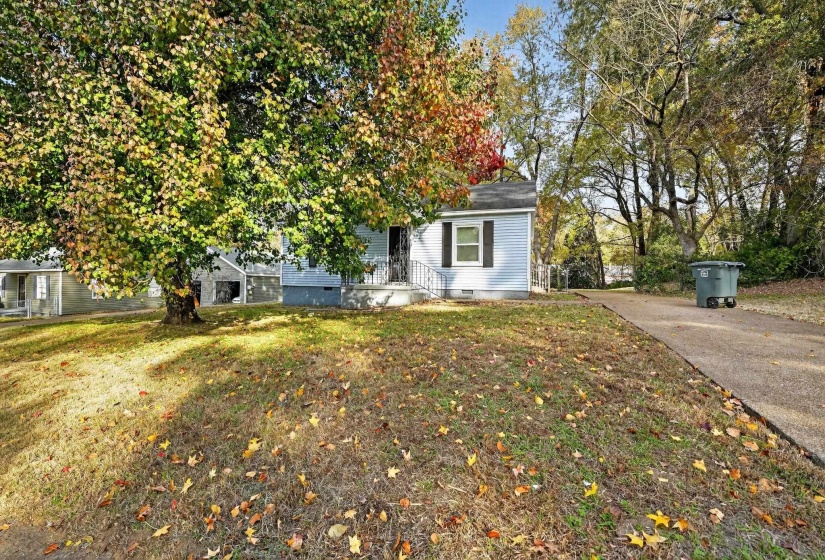 View of property hidden behind natural elements with crawl space and a front lawn