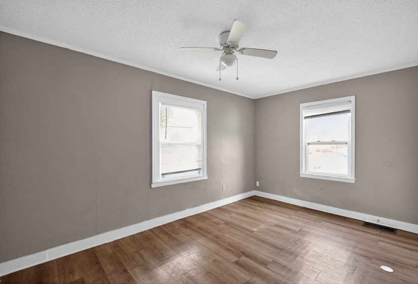Empty room with light wood-type flooring, ornamental molding, a textured ceiling, and a ceiling fan