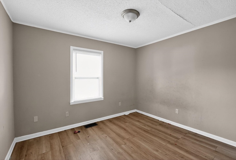 Unfurnished room featuring light wood finished floors, a textured ceiling, and crown molding