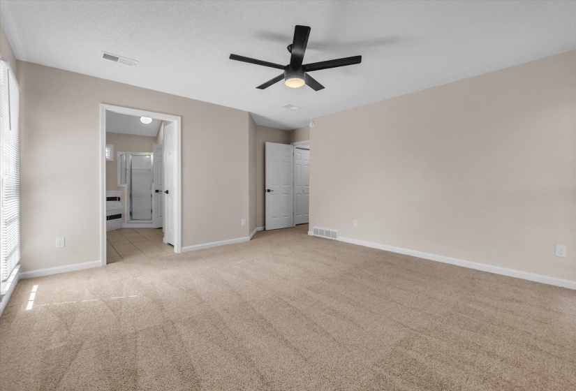 Unfurnished bedroom featuring light colored carpet, ceiling fan, and ensuite bathroom
