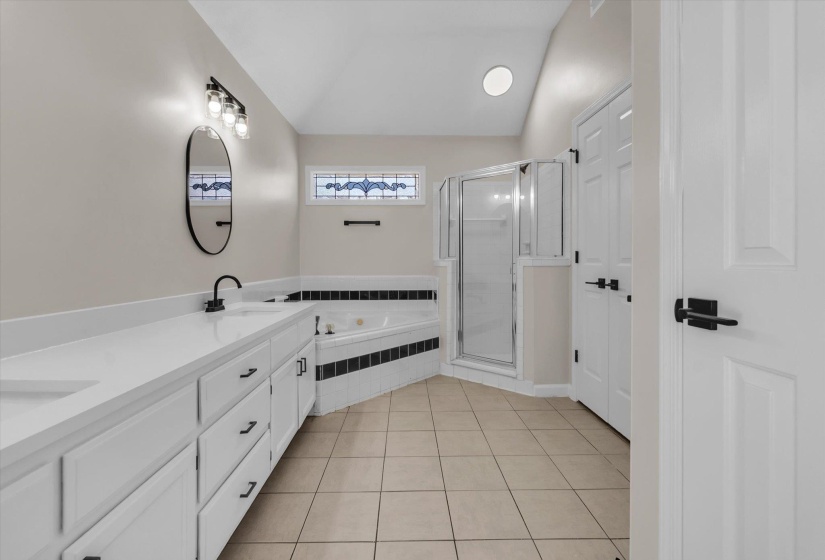 Full bath featuring lofted ceiling, a stall shower, double vanity, a garden tub, and light tile patterned floors
