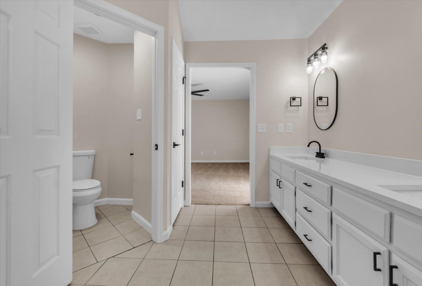 Full bath featuring double vanity, light tile patterned floors, and light carpet