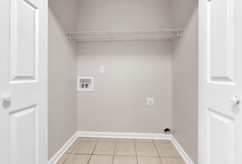 Laundry area with hookup for a washing machine, light tile patterned flooring, and electric dryer hookup