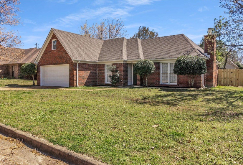 View of front of home featuring a chimney, brick siding, a shingled roof, driveway, and a garage