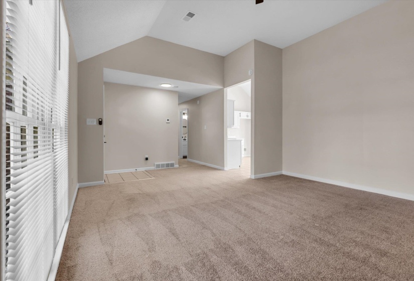 Spare room with lofted ceiling, light carpet, and a ceiling fan