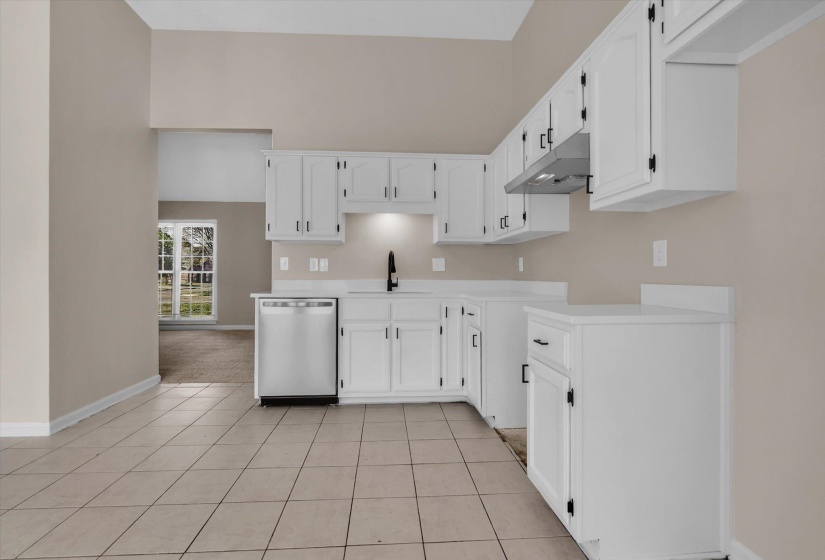 Kitchen with white cabinets, dishwasher, light countertops, and a high ceiling