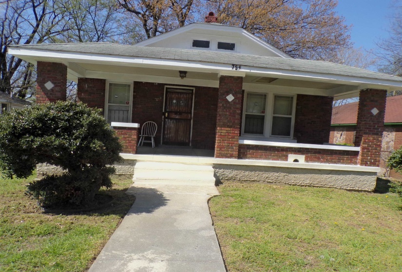 View of front of home featuring brick siding, a porch, and a front lawn