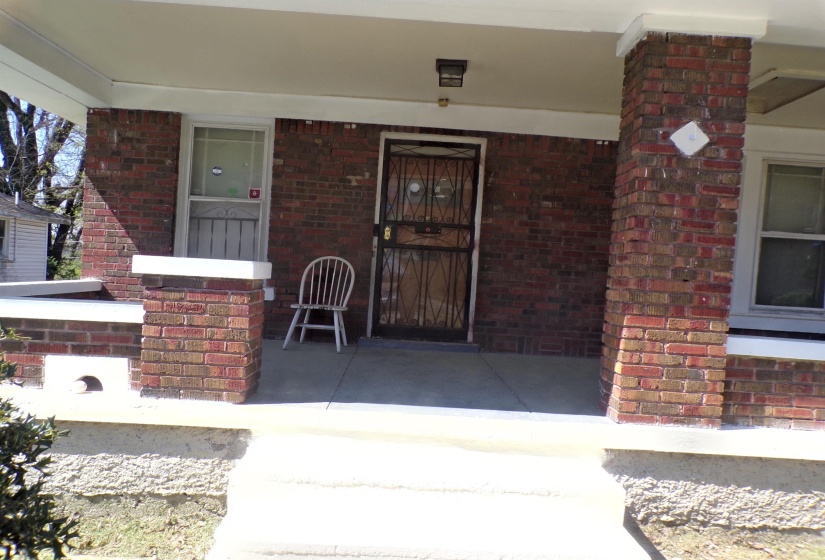 Doorway to property featuring a porch and brick siding