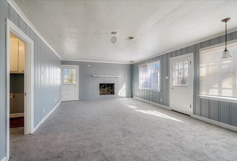 Unfurnished living room featuring crown molding, a fireplace, carpet floors, and wood walls