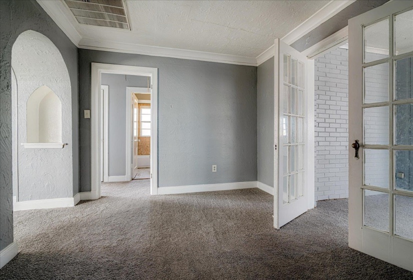 Unfurnished room with a textured wall, crown molding, french doors, carpet, and a textured ceiling