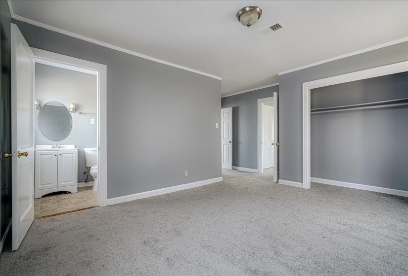 Unfurnished bedroom with light carpet, a closet, crown molding, and connected bathroom