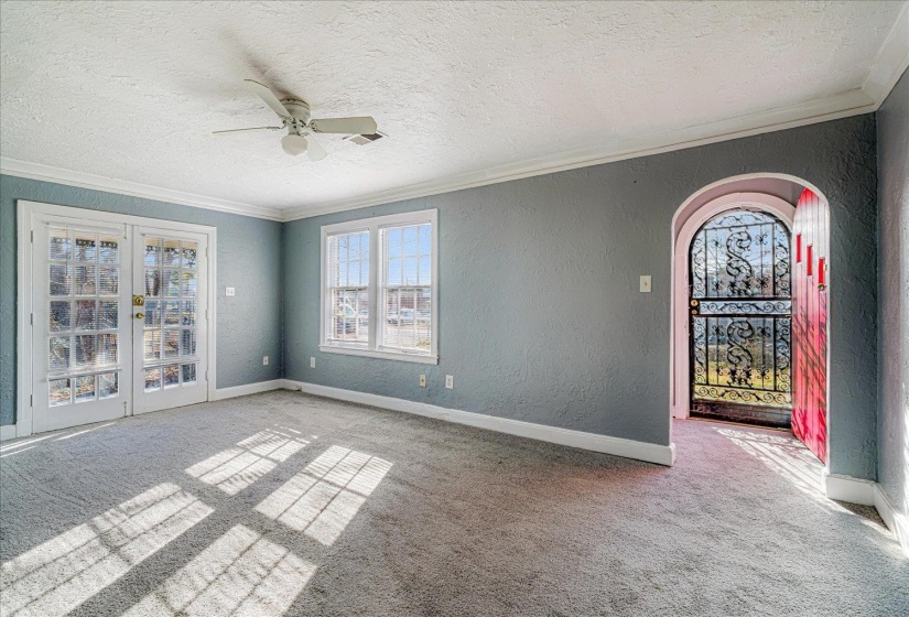 Empty room with a textured wall, french doors, a textured ceiling, light colored carpet, and ceiling fan