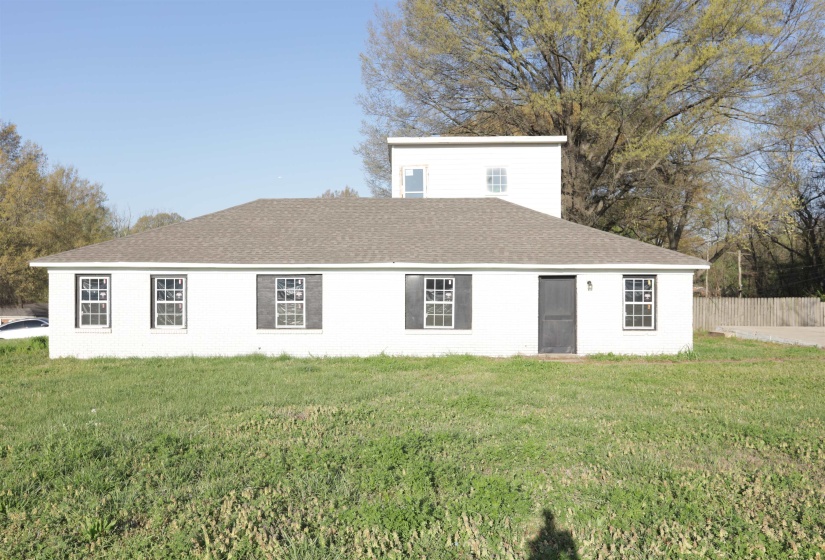 Back of property featuring a shingled roof and brick siding
