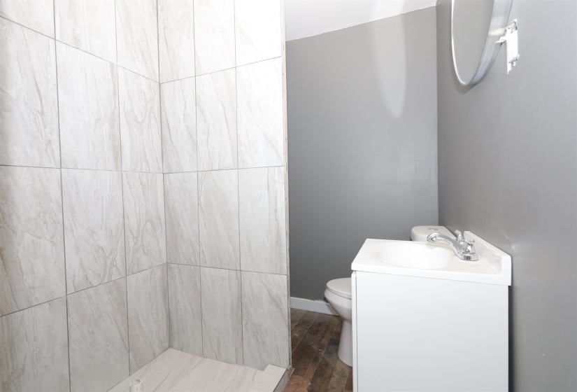 Bathroom with a tile shower, vanity, and wood finished floors