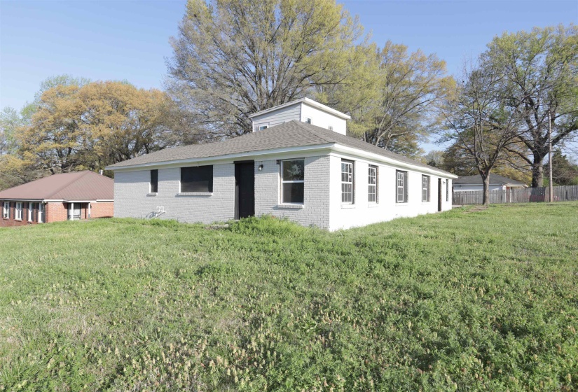 Rear view of house featuring brick siding and roof with shingles