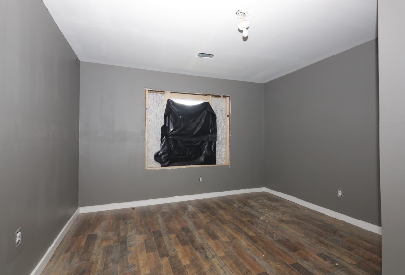 Empty room featuring dark wood-style floors and baseboards