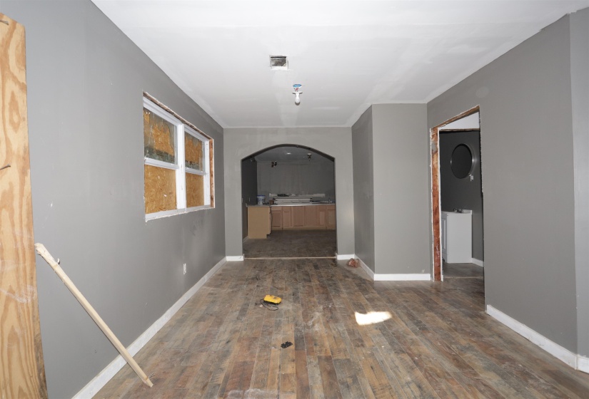 Hallway featuring arched walkways and dark wood-style flooring