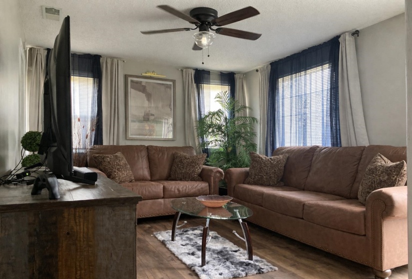 Living area featuring ceiling fan, wood-type flooring, and a textured ceiling