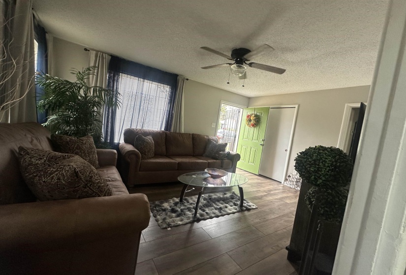 Living area featuring a textured ceiling, wood-type flooring, and a ceiling fan