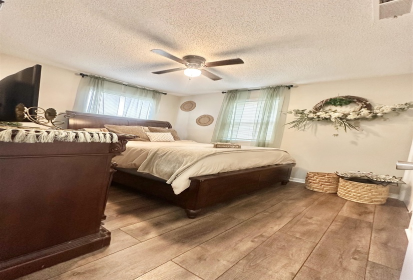 Bedroom with wood-type flooring, a ceiling fan, and a textured ceiling