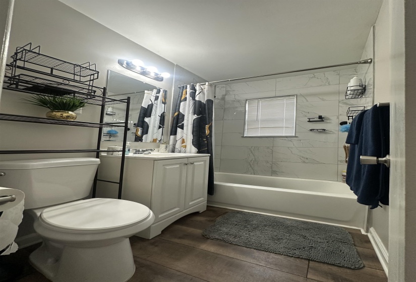 Bathroom with vanity, shower / tub combo with curtain, and dark wood-style floors