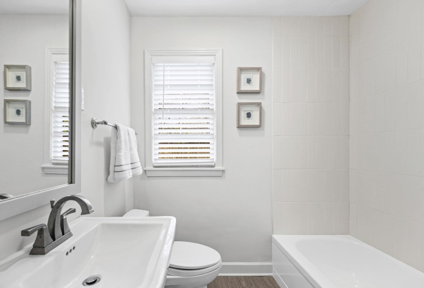 Full bathroom with toilet and dark wood-style flooring