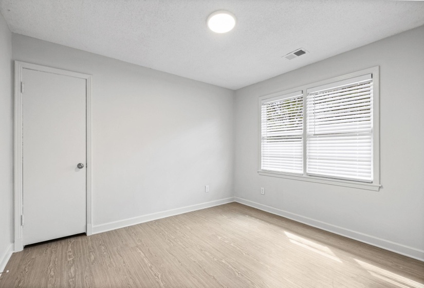 Empty room with a textured ceiling and light wood finished floors