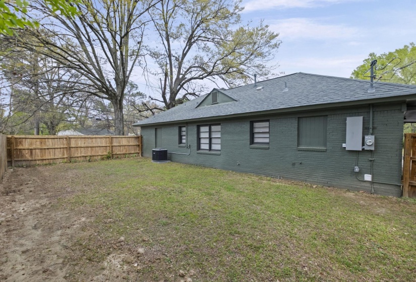 Back of house featuring a fenced backyard, a shingled roof, and brick siding